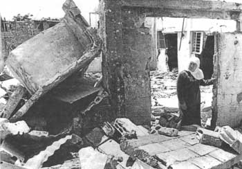 A Palestinian refugee trudges away from the wreckage of her home, destroyed in an Israeli attack on a refugee camp in southern Lebanon during Israel's 1982 invasion