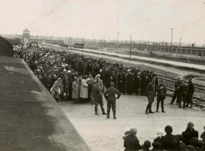 Jews deported from Hungary to Auschwitz-Birkenau in late spring/early summer of 1944, lined up on the railway platform: women and children on the left, men on the right. (Auschwitz Album)