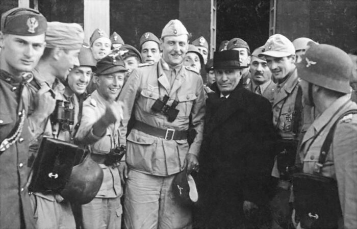 Group photo after Mussolini’s rescue. Mussolini in a black coat and hat, Skorzeny next to him with binoculars.